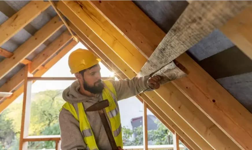 Attic insulation contractor inspection Insulation contractor checking attic roof insulation with a hard hat