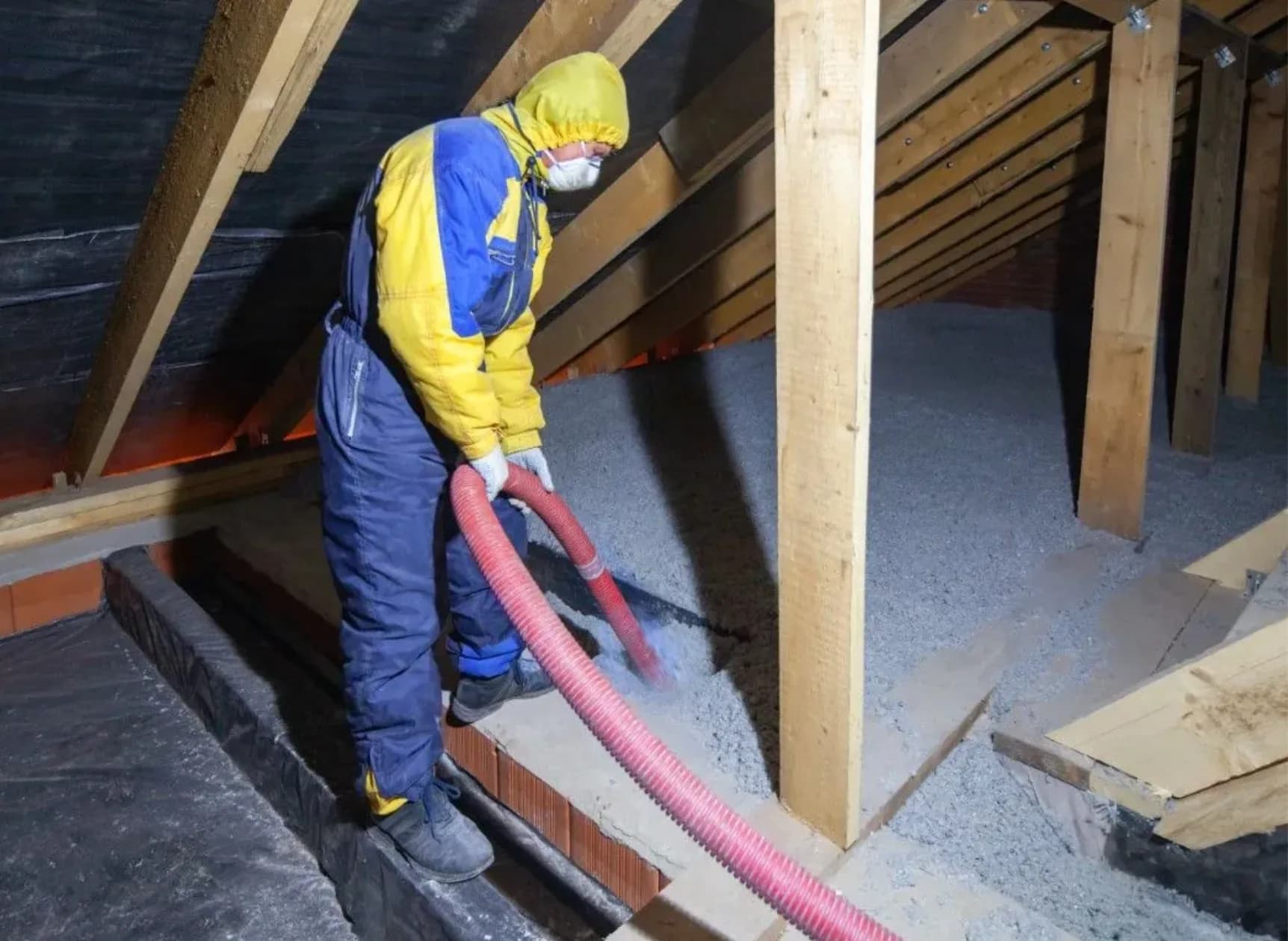 Loose fill attic insulation install Technician blowing loose fill attic insulation between roof framing